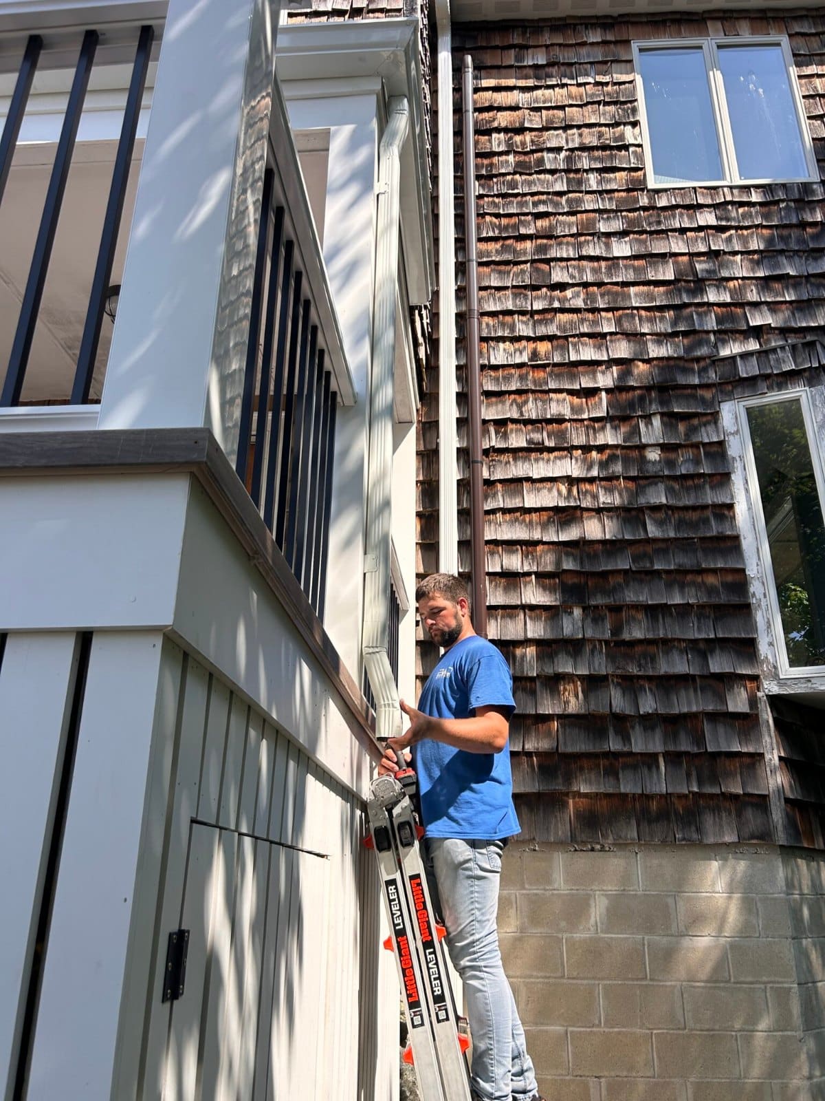 Gutter IQ technician repairing a gutter downspout on a Boston-area home
